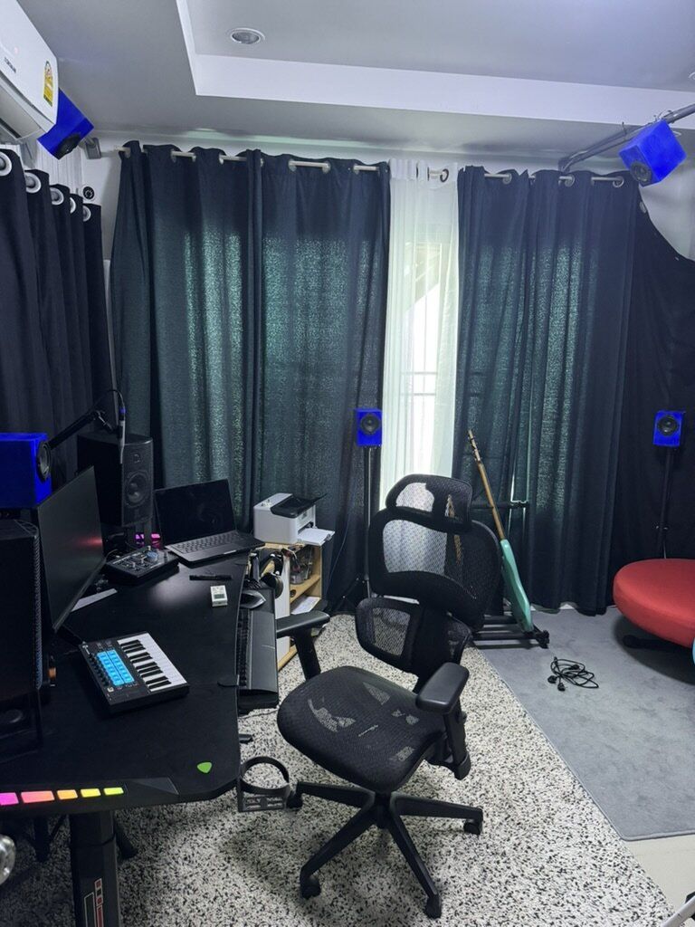 A listening room with monitors set up around the desk, including on the ceiling