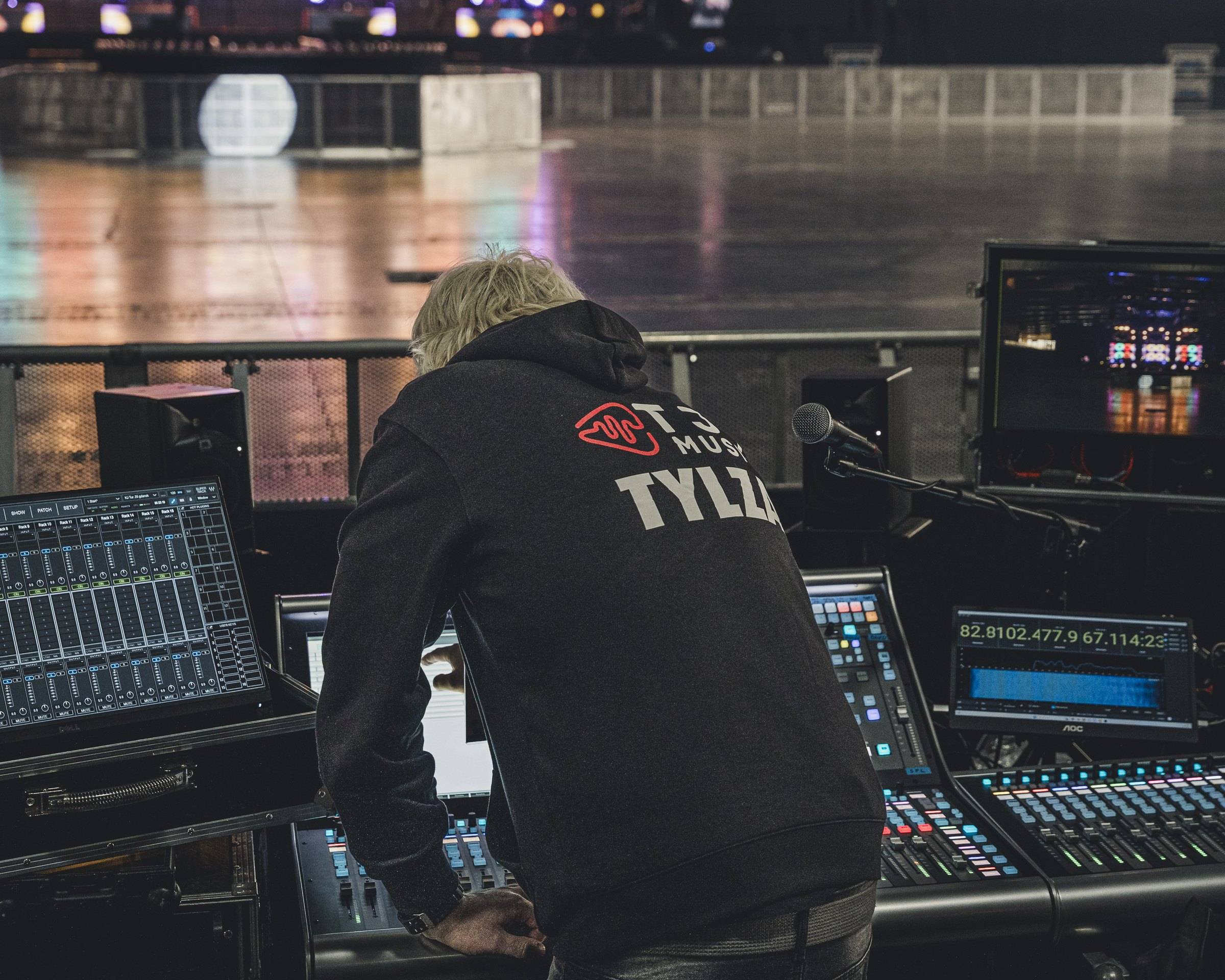 Patryk Tylza leaning over a console, TYLZA printed on his hoodie